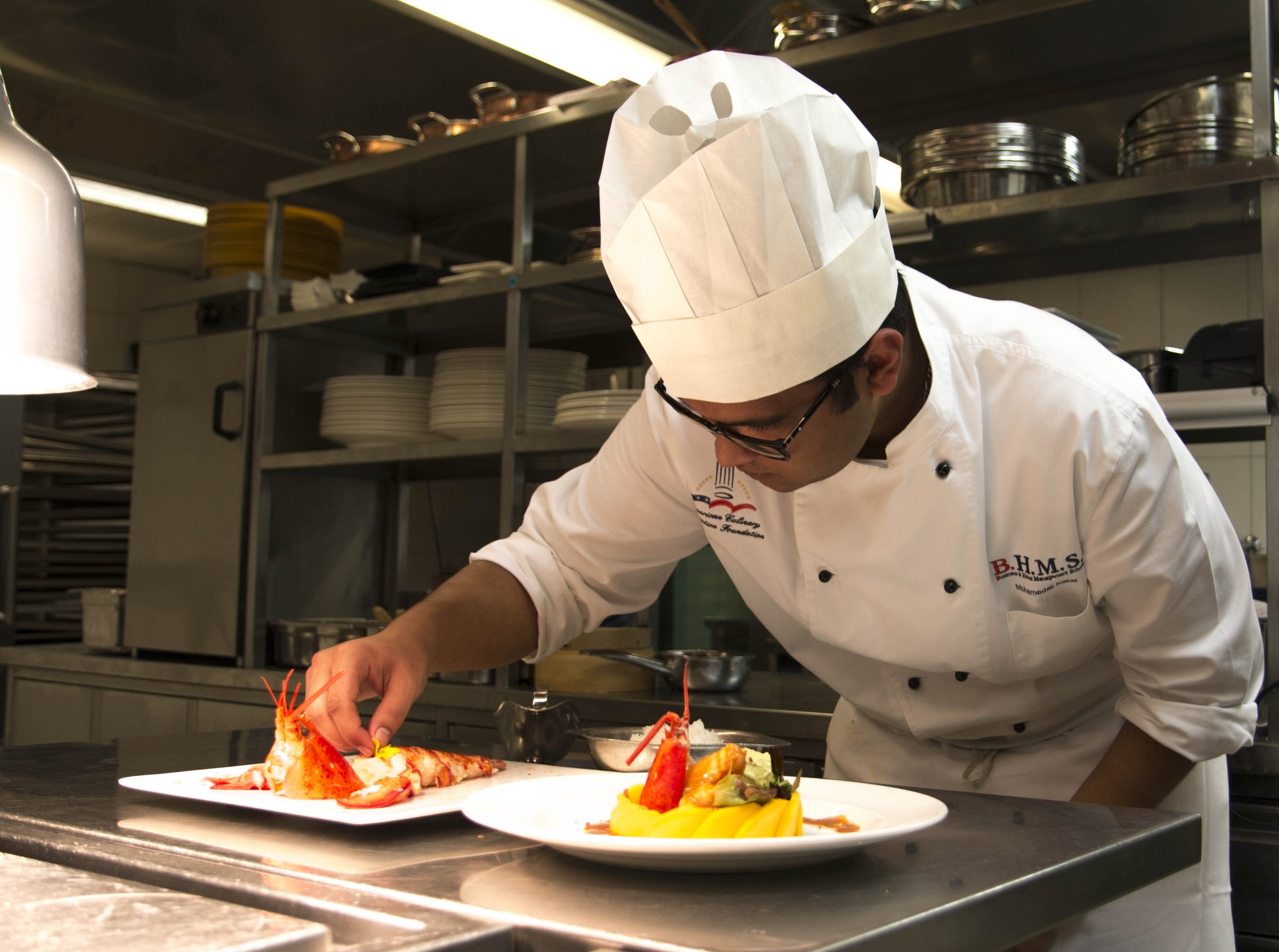 BHMS culinary intern plating lobster dishes during a Swiss hotel placement
