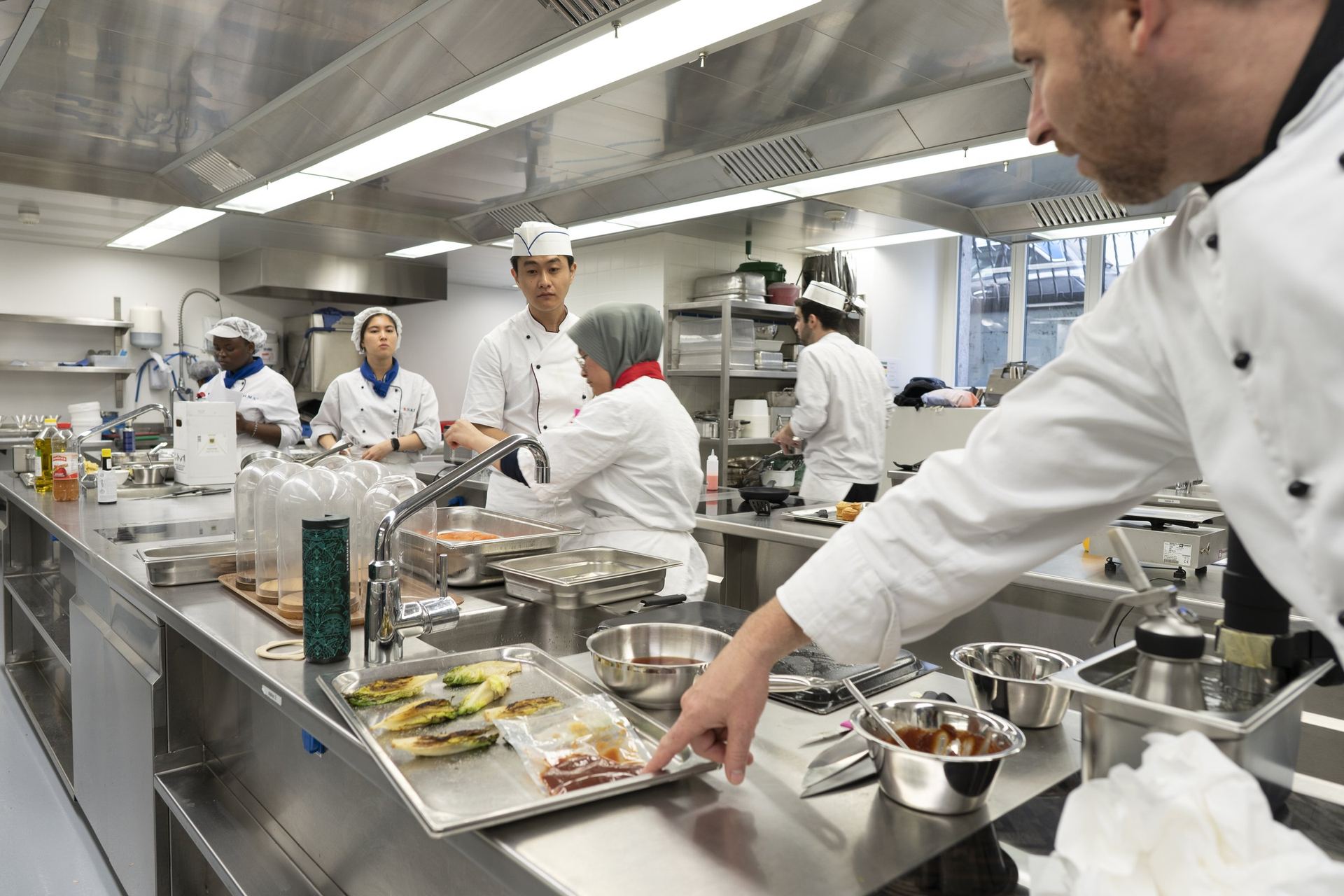BHMS teaching kitchen with chef instructor and students at individual stations